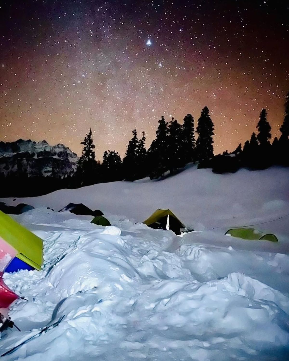 Stars and the Milky Way above tents in the snow