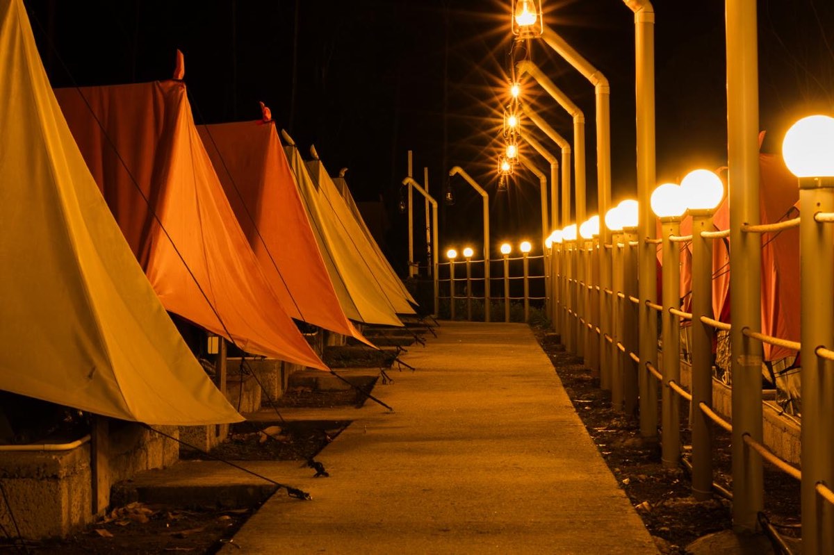 Lantern-lit path between tents at the camp after dark