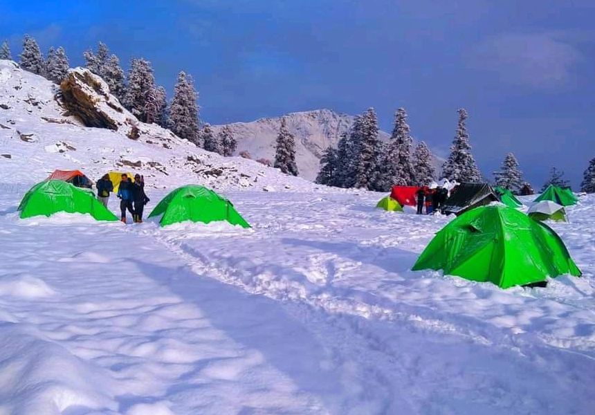 Green tents at a snowy camp in the forest