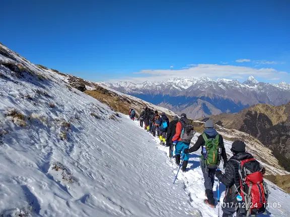 Trekkers on a ridge trail with mountains beyond