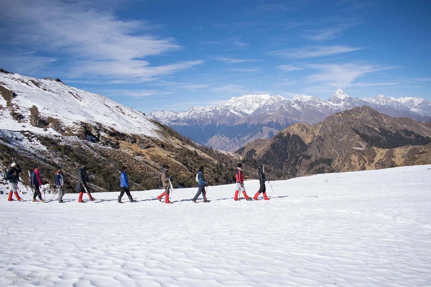 A line of trekkers crossing snow below the Garhwal Himalayas on the Kuari Pass trail