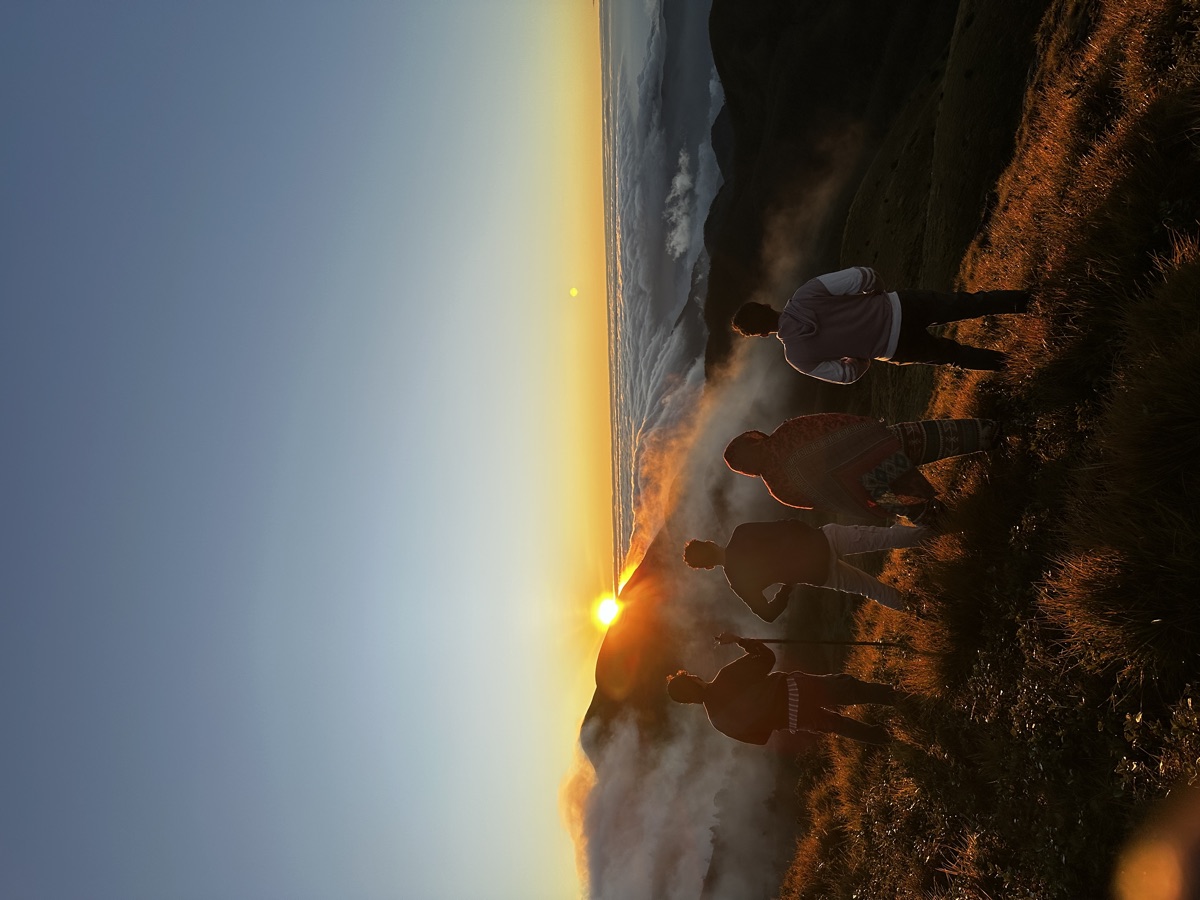 A small group watching the sunrise above the clouds